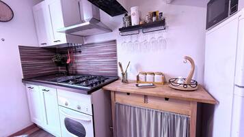 Una cucina compatta con piano cottura a gas, forno e un piccolo bancone con barattoli e utensili.