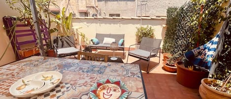 An outdoor patio with a patterned table, chairs, and a decorative plate.