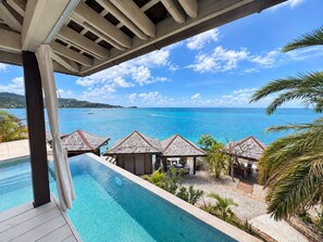 Vista de la piscina con un océano azul cristalino y una isla a lo lejos.