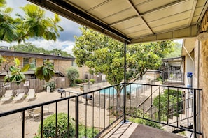 A covered outdoor area with a pool, lounge chairs, and a staircase leading to a building. - Lovely 1-bedroom condo with AC, Wifi, Pool, Washer Dryer in vibrant Dallas (Dallas)
