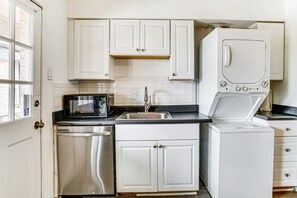 A compact kitchen with white cabinets, a microwave, a dishwasher, and a washing machine. - Lovely 1-bedroom condo with AC, Wifi, Pool, Washer Dryer in vibrant Dallas (Dallas)