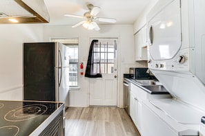A compact kitchen with a refrigerator, stove, microwave, and oven. There's a ceiling fan and a window with a view. - Lovely 1-bedroom condo with AC, Wifi, Pool, Washer Dryer in vibrant Dallas (Dallas)