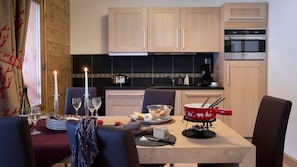 A dining area with a table set for two, a candle, wine glasses, and a red pot on the table. - Résidence CGH les Chalets de Flambeau (Val-Cenis)