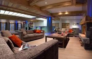 A spacious lobby with high ceilings, wooden beams, and a stone fireplace. - Résidence CGH les Chalets de Flambeau (Val-Cenis)