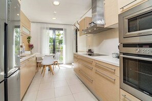 Eine moderne Küche mit einem Siemens-Ofen, ein Essbereich mit Tisch und Stühlen sowie ein Blick ins Grüne.