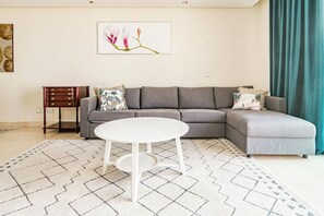 A living room with a grey sofa, a white round table, and a patterned rug. - BVQ - Stunning Sea & Golf View Terrace (Marbella)