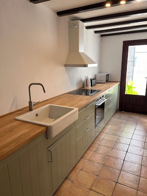 A kitchen with a sink, stove, microwave, and a window with a view. - El Portet, Moraira - Fully Refurbished 3-Bed With Pool, 6-Min Walk To The Beach (Moraira)