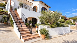 A two-story building with a staircase leading to an entrance, surrounded by potted plants and a white wall. - El Portet, Moraira - Fully Refurbished 3-Bed With Pool, 6-Min Walk To The Beach (Moraira)