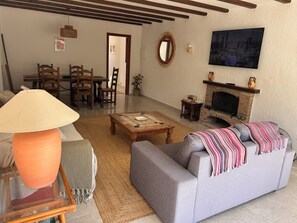A living room with a sofa, coffee table, lamp, fireplace, television, and dining area. - El Portet, Moraira - Fully Refurbished 3-Bed With Pool, 6-Min Walk To The Beach (Moraira)