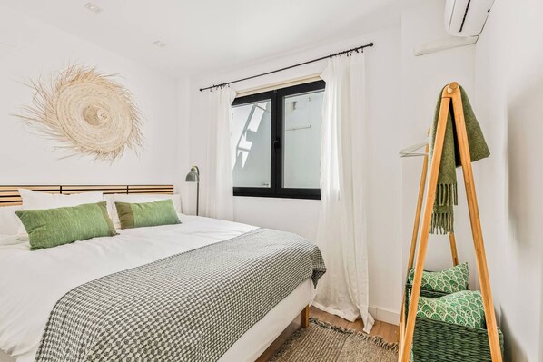 Une chambre à coucher avec un lit, une fenêtre avec des rideaux, un lampadaire et une échelle en bois recouverte d’un tissu vert.