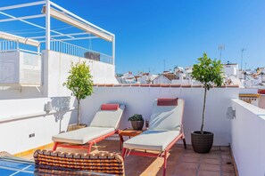 Terrassa al terrat amb dos relaxants, una taula petita i dues plantes en testos.
