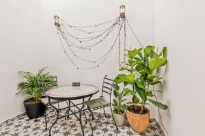 A small, round table with chairs, surrounded by potted plants, and a string of lights hanging from the ceiling. - Coral8 - Top modern townhouse in Estepona old town (Estepona)