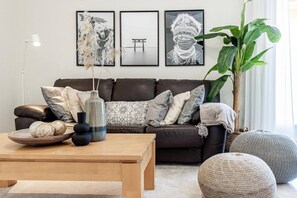 A modern living room with a dark sofa, decorative pillows, a wooden coffee table, and a large green plant. - DN11-2 bedroom apartment close to Puerto Banus (Marbella)