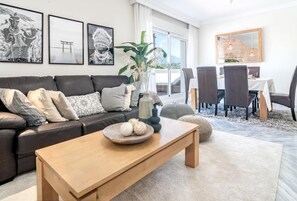A modern living room with a sofa, coffee table, and dining area. - DN11-2 bedroom apartment close to Puerto Banus (Marbella)