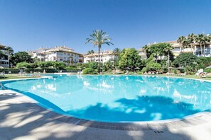 A swimming pool with a clear blue water surface, surrounded by a paved deck. - DN11-2 bedroom apartment close to Puerto Banus (Marbella)