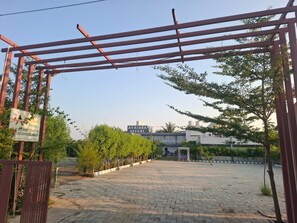 A paved entrance area with a sign for 'AVATAR RESORT' and a gated entrance. - Avatara Resort Sasan Gir (Talala)