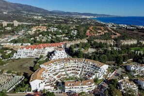 A coastal resort with a central circular building surrounded by residential areas and a view of the sea. - ELD2-Luxury 3 Bedroom Penthouse in Nueva Andalucia (Marbella)