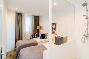 A hotel room with two beds, a shower, a bedside table with a lamp, and a large mirror. - ELD2-Luxury 3 Bedroom Penthouse in Nueva Andalucia (Marbella)
