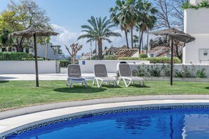 Un área junto a la piscina con sillones de descanso y una piscina azul cristalina.