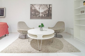 A modern room with a round white table, two armchairs, a red tablecloth, a framed picture on the wall, and a white bookshelf. - ELd41- Prime location, pool views and evening sun (Marbella)