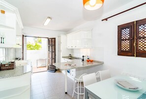 A modern kitchen with white cabinets, a granite countertop, and a dining area with a table and chairs. - EN- Cozy Andalusian style townhouse in Marbella (Marbella)