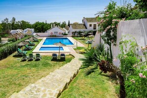 A swimming pool with lounge chairs and umbrellas, surrounded by greenery and white buildings. - EN- Cozy Andalusian style townhouse in Marbella (Marbella)
