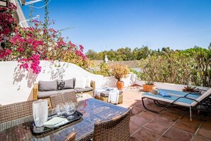An outdoor patio with wicker furniture, a glass-top table, and a lounge chair. - EN- Cozy Andalusian style townhouse in Marbella (Marbella)