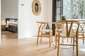 A modern room with a wooden floor, a round mirror on the wall, a bed with a grey headboard, and a dining area with wooden chairs. - GO- Golden Banus by Roomservices (Marbella)