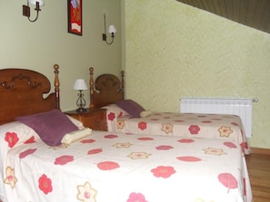 Un dormitorio con dos camas, una mesita de noche, una lámpara y un radiador.