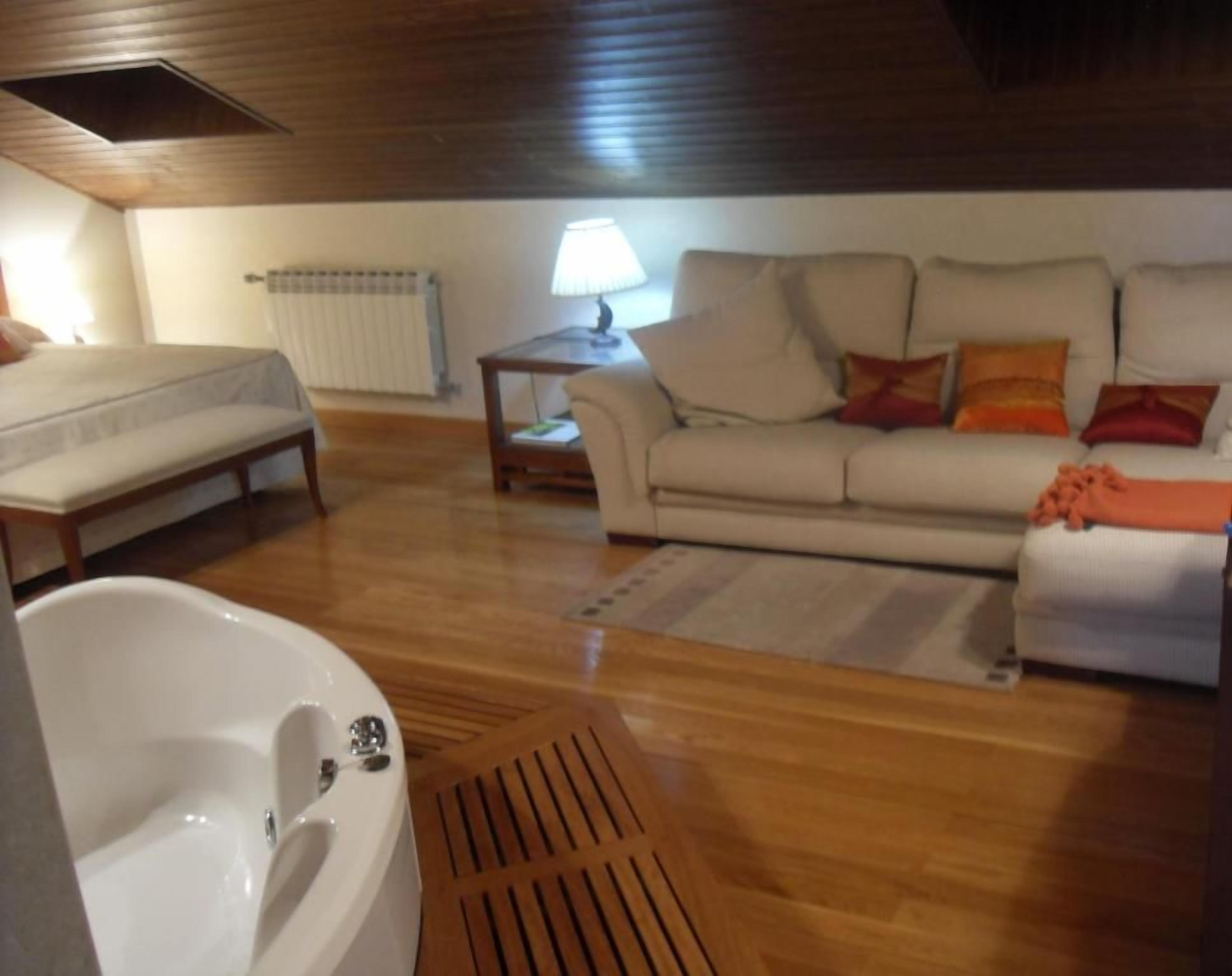 A room with a bed, a sofa, a lamp, and a radiator.