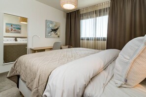 A hotel room with a large bed, a desk, a chair, a mirror, and artwork on the walls. - INF26H- Comfortable and spacious city apartment (Estepona)