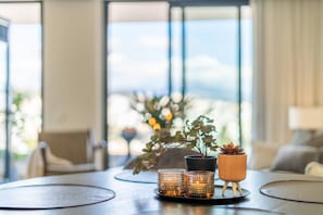 A modern living room with a large window, a coffee table, and decorative items including a plant and candles. - INf26F - Modern and bright city apartment (Estepona)