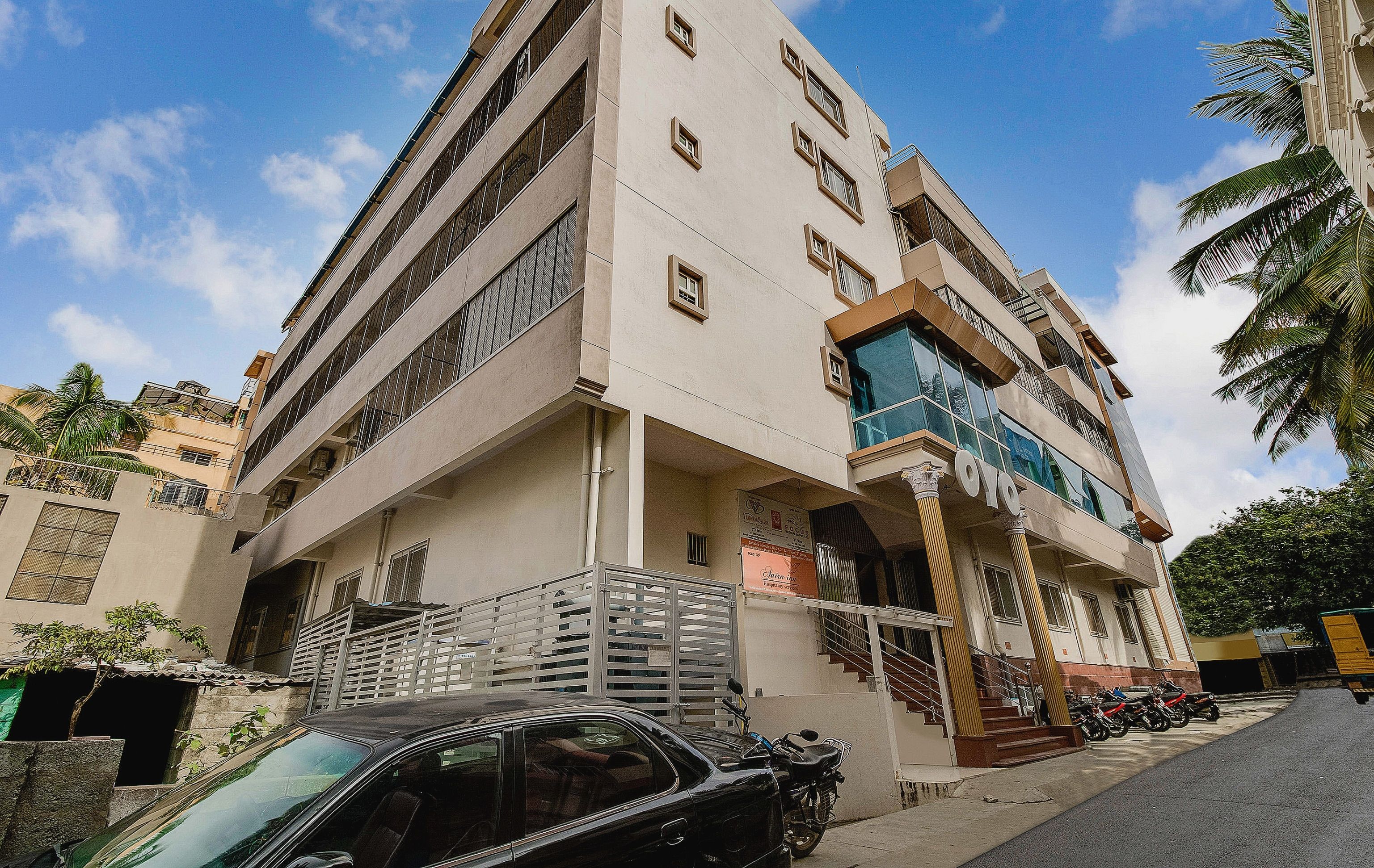A multi-story building with a balcony, a staircase, and a parked car.