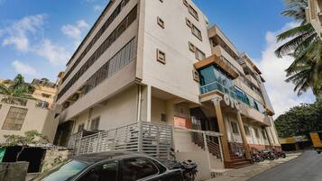 A multi-story building with a balcony, a staircase, and a parked car.