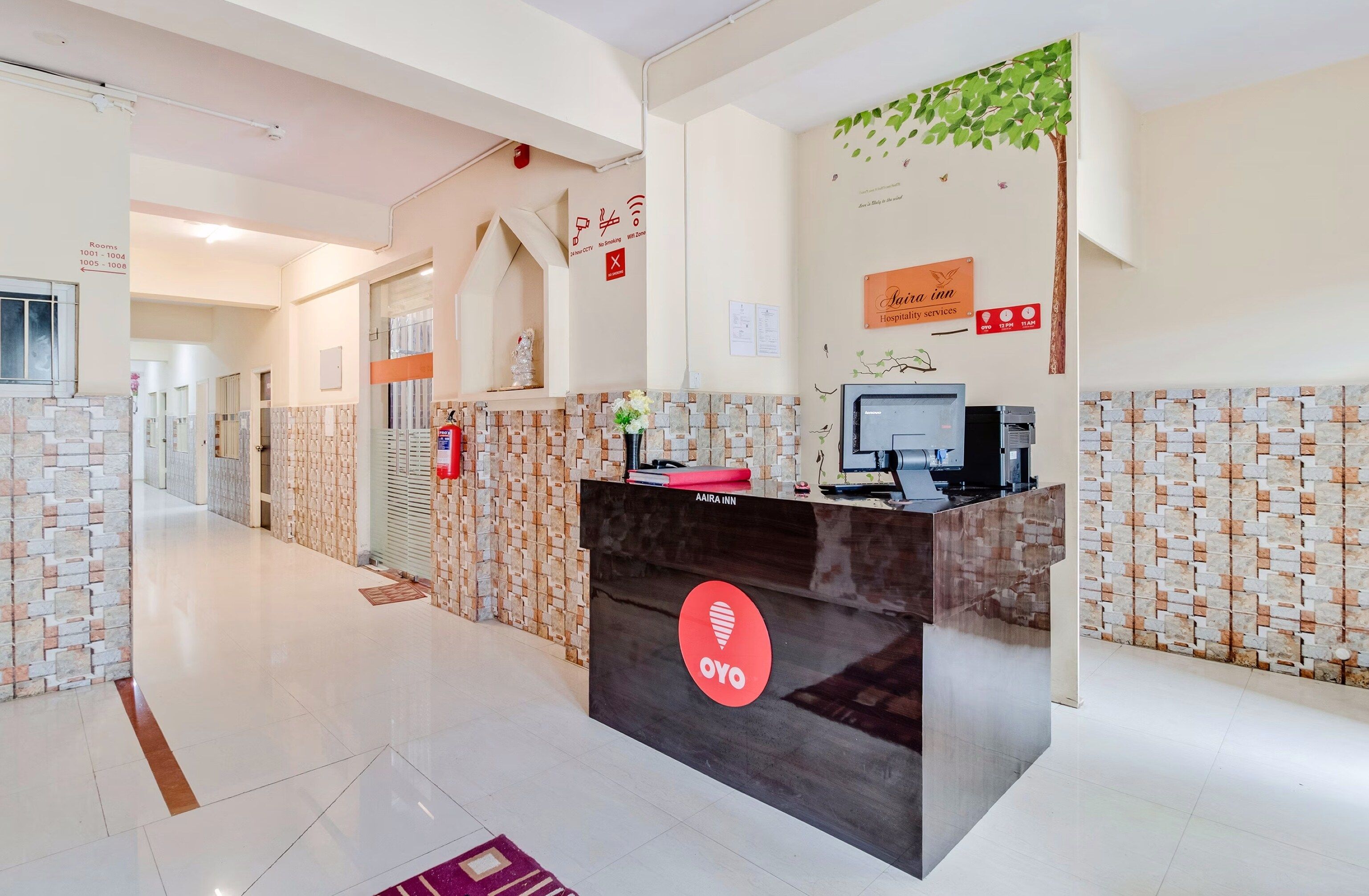 Een hotel receptie met een receptiebalie, een brandalarm en een bordje met informatie over de dienstverlening van het hotel.
