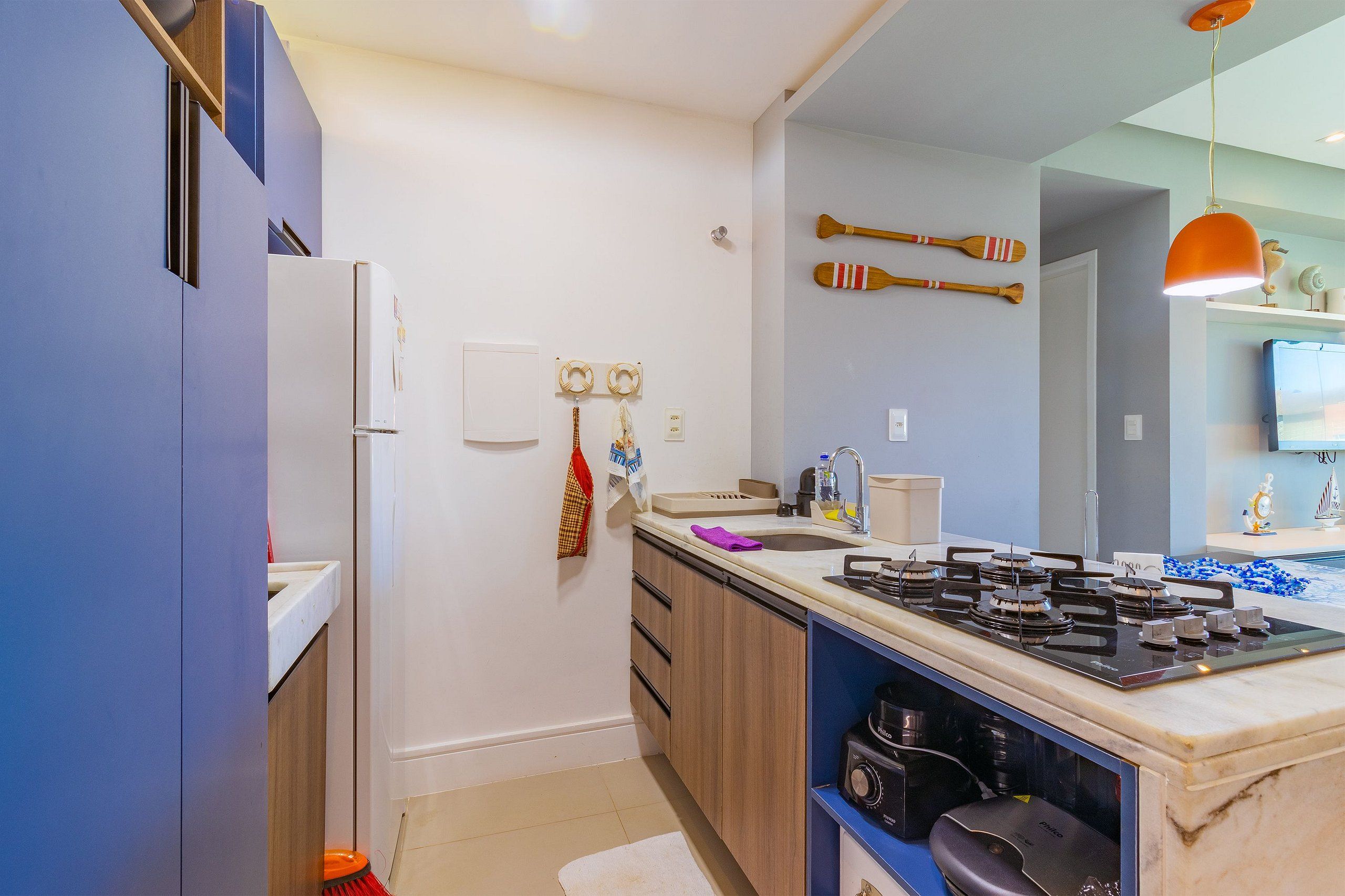Eine moderne Küche mit einem eingebauten Gasherd, Holzschränken und einem weißen Kühlschrank.