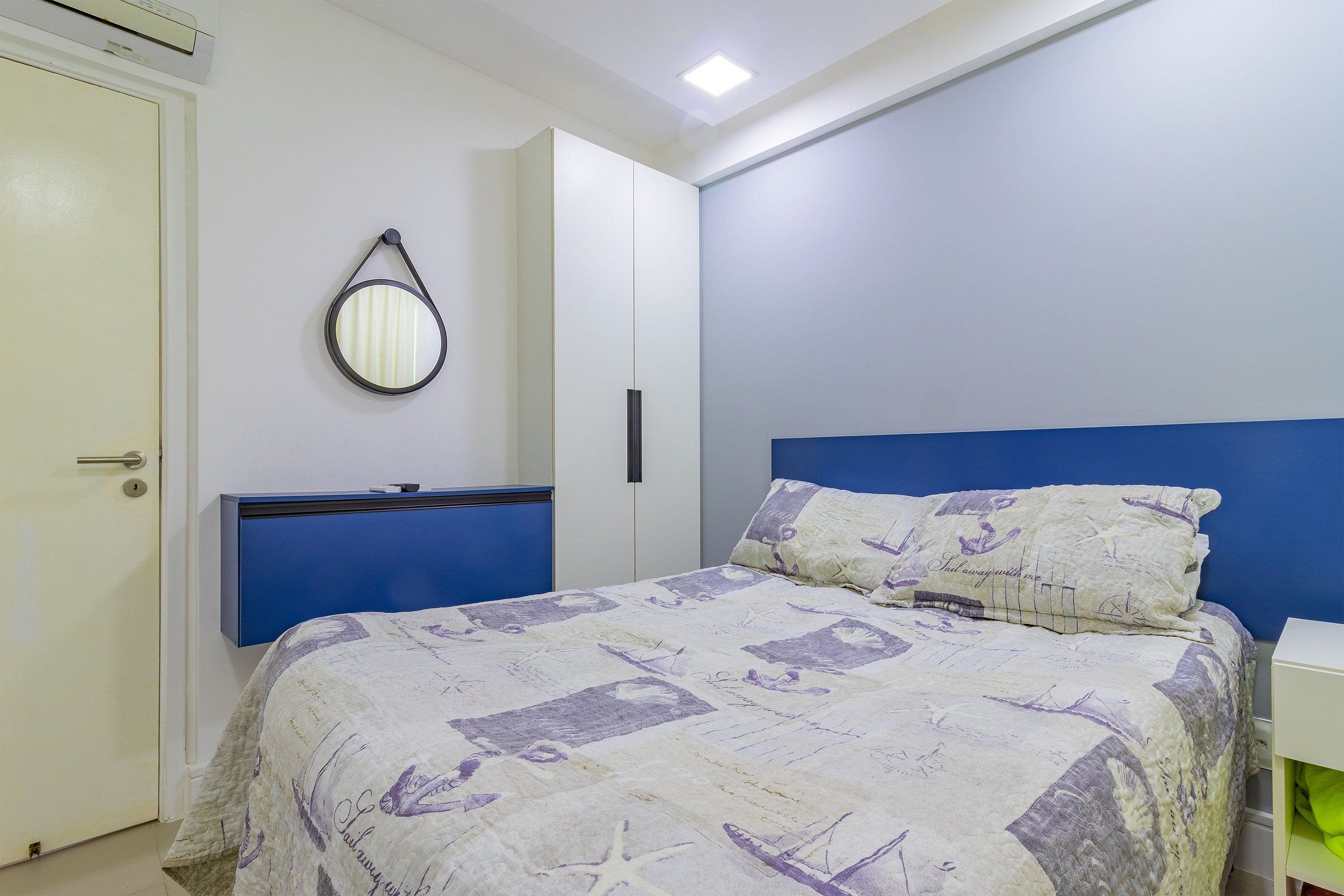 Quarto com cama, guarda-roupa, espelho e mesa de cabeceira.