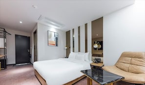 A hotel room with a bed, a sofa, a small table, a door, and a wall-mounted artwork. - Hotel about (Cheongju)
