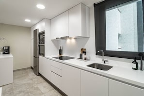 A modern kitchen with white cabinetry, a built-in oven, a stove, and a large window. - IN33K- Stunning city apartment close to beaches (Estepona)