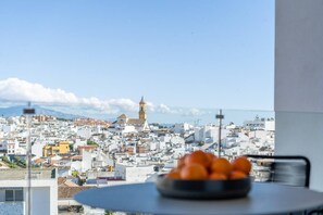 A cityscape with a prominent tower, a table with oranges, and a clear sky. - INf34I - Modern & bright city apartment (Estepona)