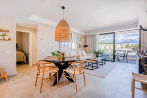 A spacious living area with a dining table, sofas, and a balcony with a city view. - INf34I - Modern & bright city apartment (Estepona)
