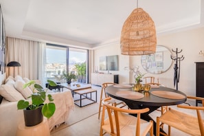 A modern living room with a dining area, large windows, and a city view. - INf34I - Modern & bright city apartment (Estepona)