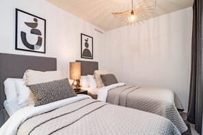 A double bed with a headboard, bedside tables, and a lamp. There are two framed abstract artworks on the wall. - INf32L- Modern city apartment, families only (Estepona)