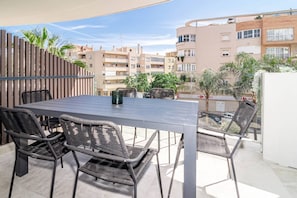 An outdoor patio with a table and chairs, surrounded by a wooden fence and buildings in the background. - INf32L- Modern city apartment, families only (Estepona)