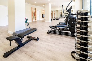 Ett gym med träningsutrustning, inklusive en bänk och löpband.