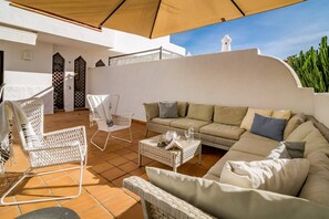 An outdoor seating area with wicker furniture, a white sofa, and a table with a glass. - GH-Modern 2 bed apartment with Pool in Estepona (Estepona)