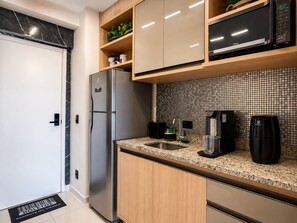 Eine moderne Küche mit Kühlschrank, Mikrowelle, Spüle und Kaffeemaschine.