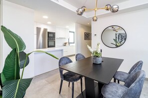 A modern dining area with a dark wooden table, grey upholstered chairs, and a vase with white flowers. - INf36K - Luxury apartment perfect location (Estepona)