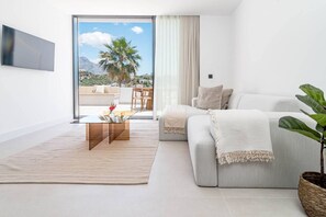 A modern living room with a sofa, a coffee table, and a view of the outdoors. - LAq75 - Beautiful Apartment with stunning view (Benahavís)
