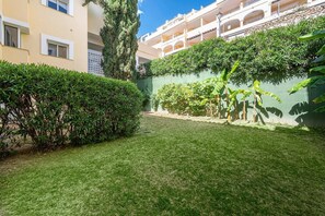 A well-maintained courtyard with a neatly trimmed lawn, a variety of shrubs, and a tall tree. - LAlq13 Stunning Frontline Golf 3 bed apt (Benahavís)